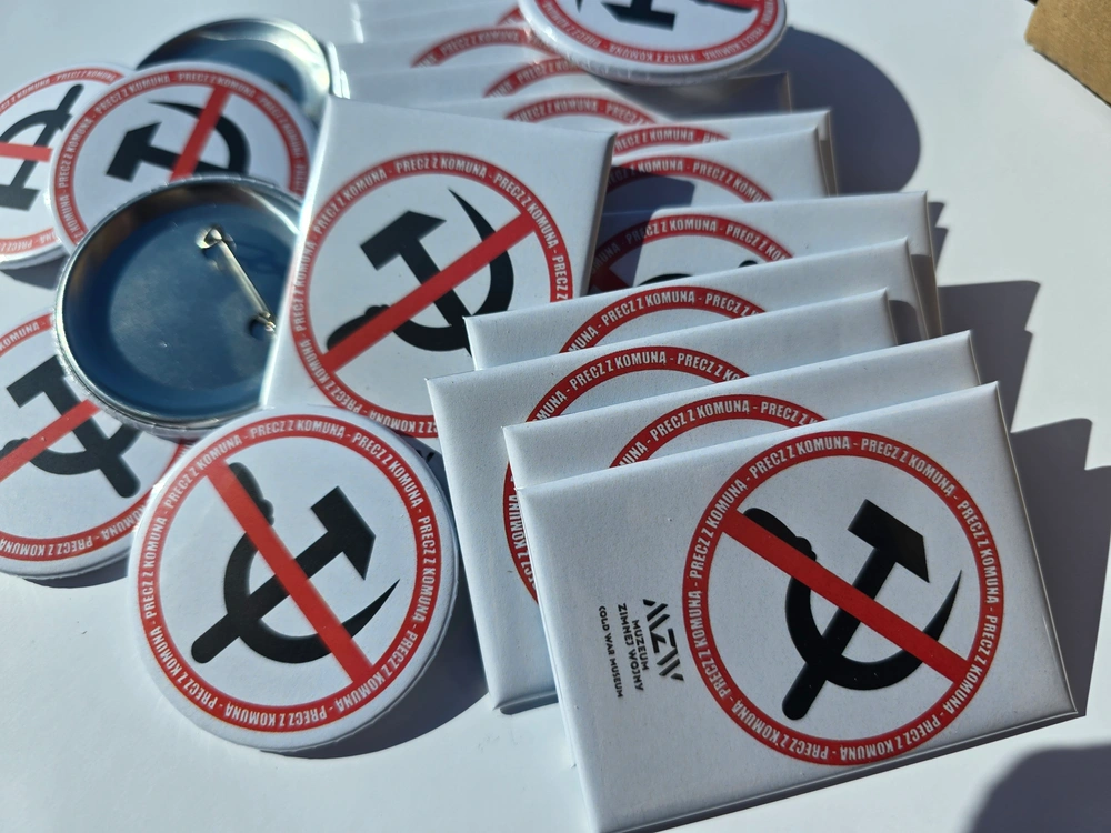 Białe prostokątne magnesy warstwowe i okrągłe przypinki z logo Muzeum Zimnej Wojny i napisem Precz z Komuną
