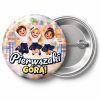 Przypinka Pierwszaki Górą Skaczące Dzieci: przypinka na pasowanie pierwszoklasisty z napisem Pierwszaki górą! – przód i aluminiowy tył z agrafką