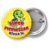 Przypinka Super Pierwszak z Nazwą Klasy Dinozaur: przypinka na pasowanie pierwszoklasisty z napisem Super Pierwszak oraz polem klasa (np. Klasa 1c) – przód i aluminiowy tył z agrafką