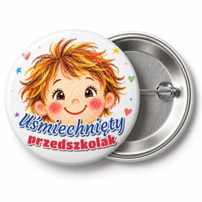 Przypinka Uśmiechnięty Przedszkolak Kredkowa Buźka: przypinka na pasowanie na przedszkolaka z napisem Uśmiechnięty przedszkolak – przód i aluminiowy tył z agrafką